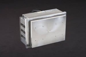 Three-quarter view of large thermoelectric cold plate cooler/heater incorporating six thermoelectric modules. The cooled aluminum plate on the front and waste heat is exhausted to high-density fins on the back. Fins are fan cooled. The fan air enters on the middle back and exhausts on sides. Operates on 24 volts DC and removes 204 watts of heat at a 0°C temperature difference relative to ambient. Internal extender blocks improve the heat pumping capacity at larger temperature differences.